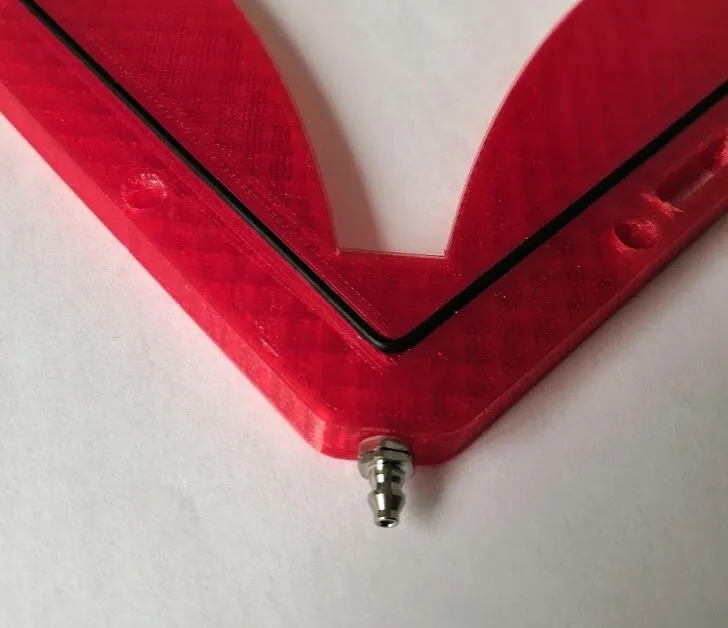 A barbed fitting screwed into one corner of the arena, with the black rubber gasket sealing the chamber